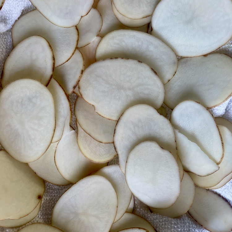 Image of Wash and slice the potatoes to make 1/8” rounds.  Give the slices a good rinse until the water runs clear.  Drain and blot them well with paper or a tea towel to remove all moisture.  Set aside.